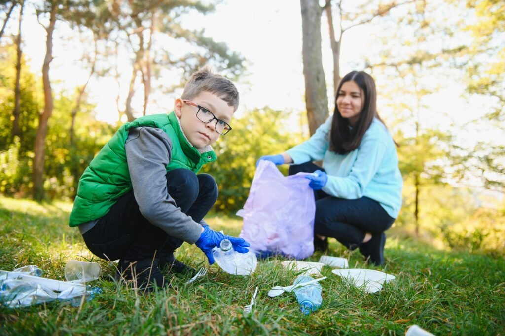 Mom teaches her son to clean up trash in nature. A woman removes plastic bottles in a bag.