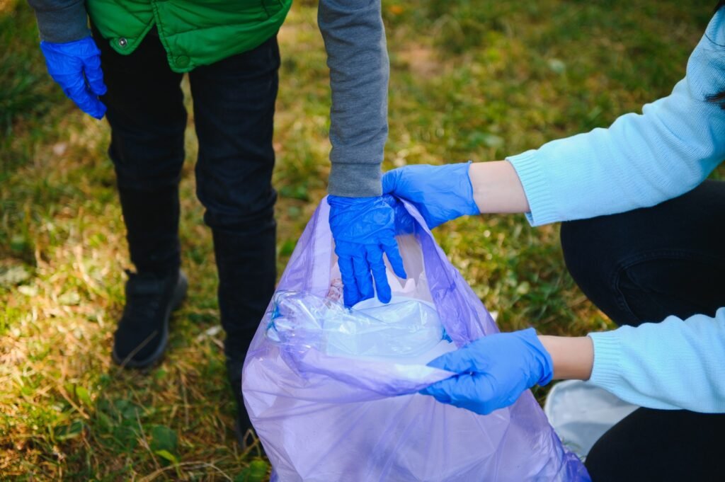 Mom teaches her son to clean up trash in nature. A woman removes plastic bottles in a bag